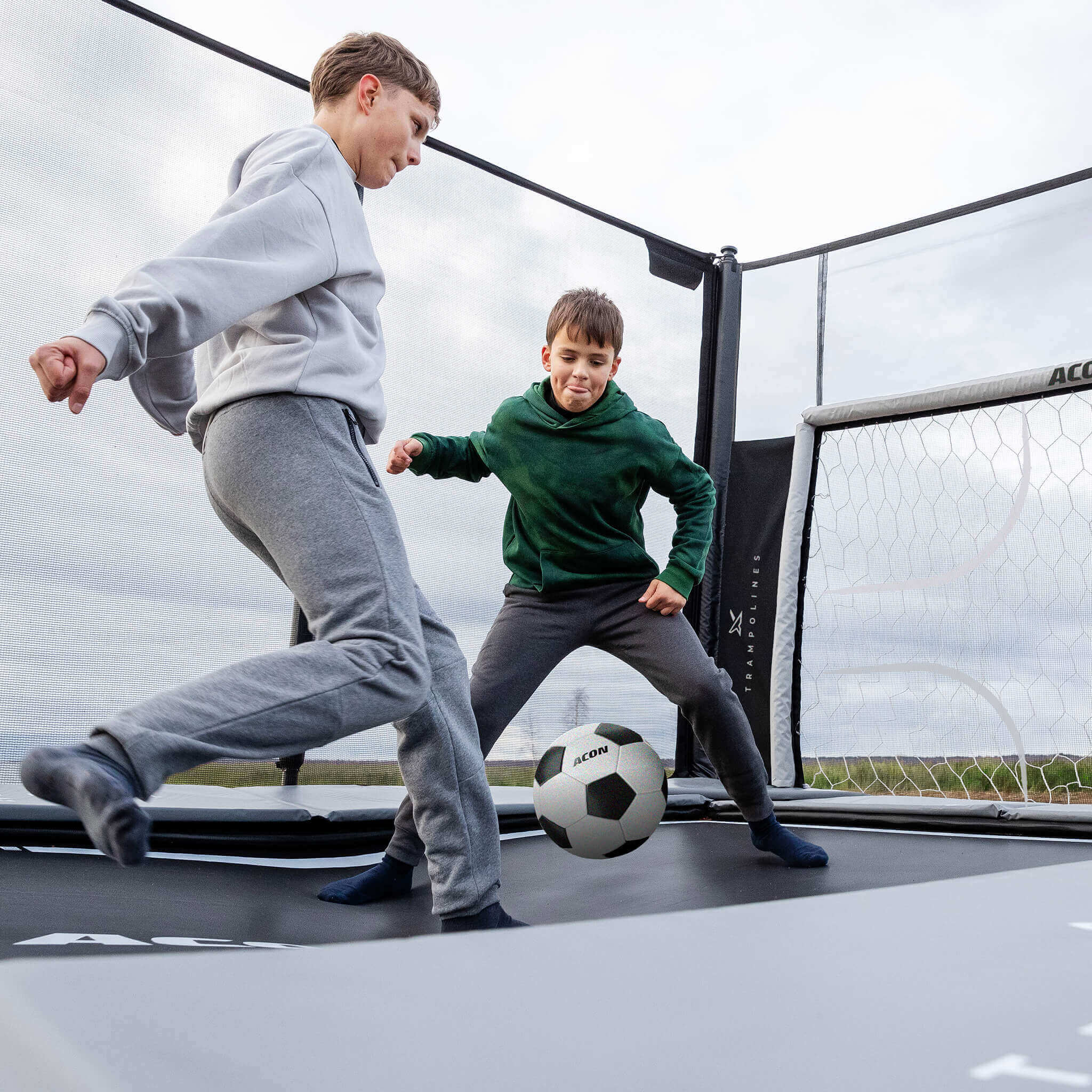 Two boys playing soccer on Acon X 17ft Trampoline with soccer panel