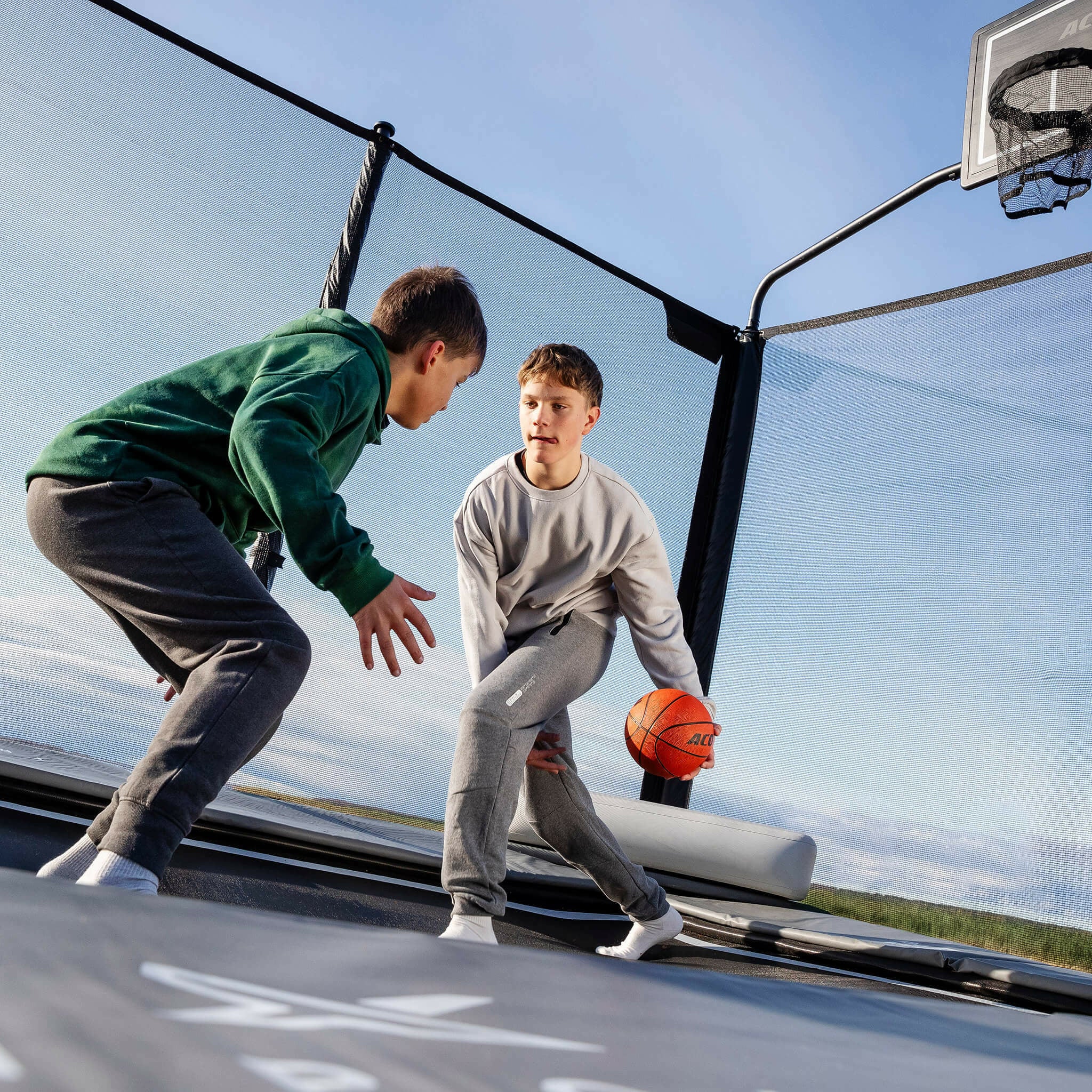 Two boys playing basketball on the Acon X Trampoline.